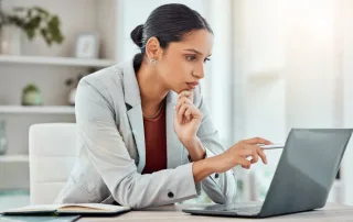 Serious, laptop and professional businesswoman sitting and reading a work email with a pen working from home