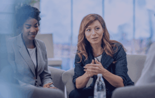 Three professionals sitting in a lounge talking around a coffee table